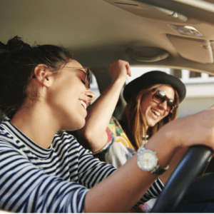 Two women dancing to music in the car