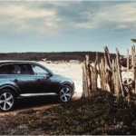 Car driving onto beach carefully through wooden fence