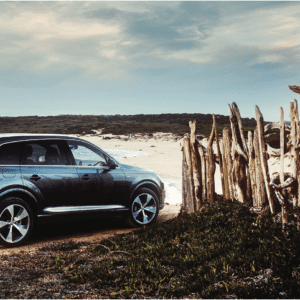 Car driving onto beach carefully through wooden fence
