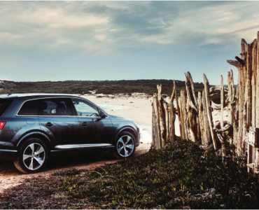Car driving onto beach carefully through wooden fence
